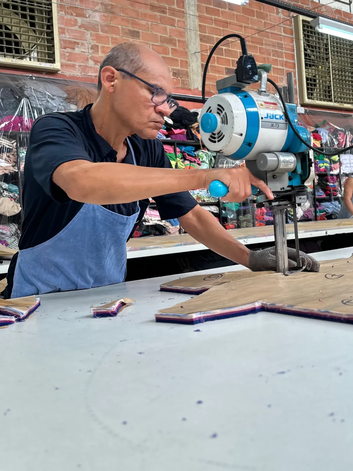 Cortador usando máquina de corte sobre o enfesto de tecido